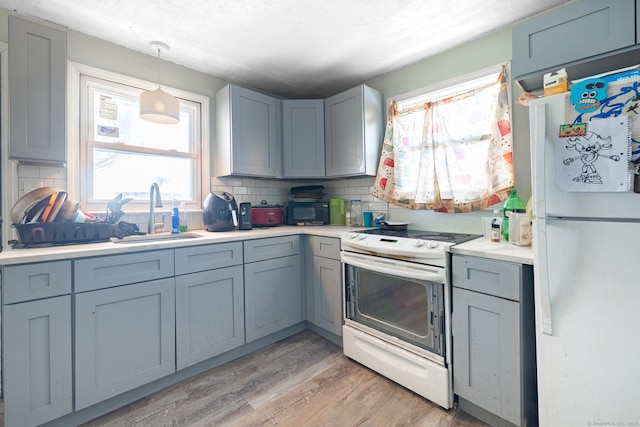 kitchen with sink, electric range oven, light wood-type flooring, white fridge, and backsplash