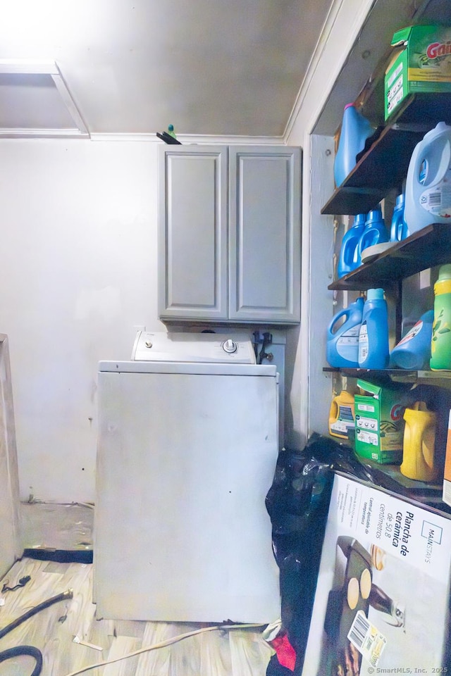 clothes washing area with crown molding, cabinets, and washer / dryer