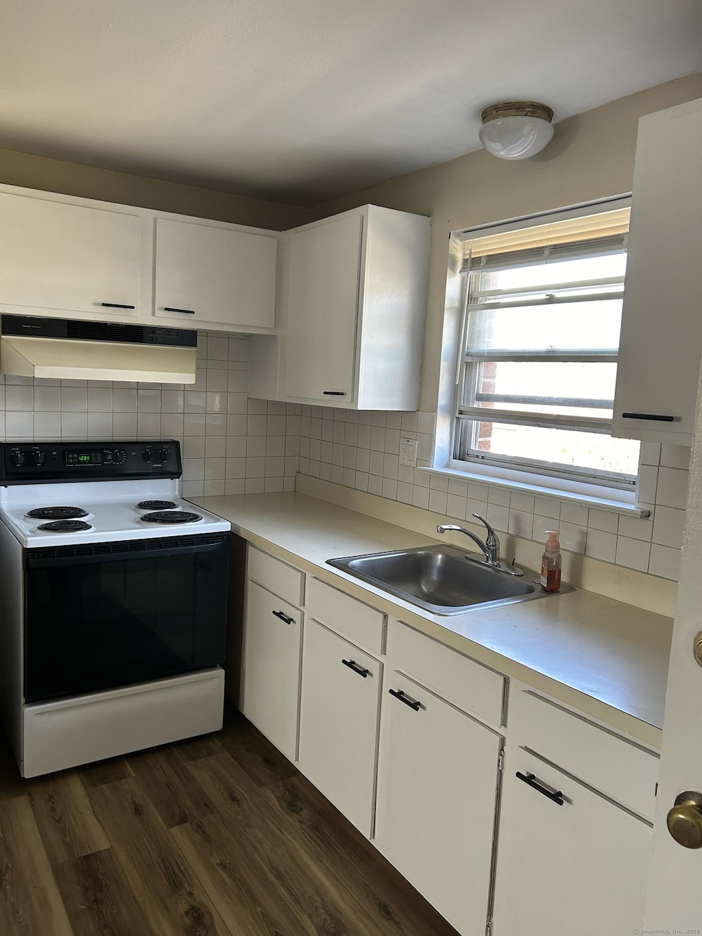 kitchen with range with electric stovetop, dark hardwood / wood-style floors, sink, white cabinets, and decorative backsplash