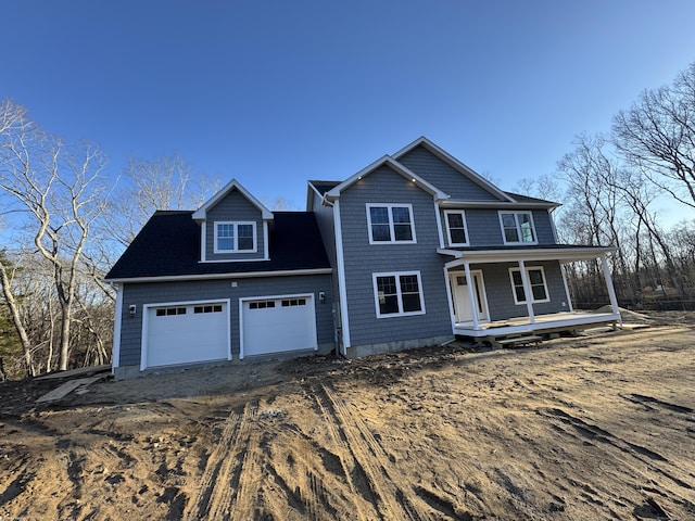 view of front of house featuring an attached garage, dirt driveway, and a porch