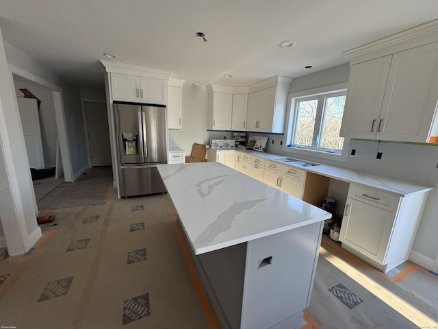 kitchen featuring a center island, recessed lighting, white cabinets, light stone countertops, and stainless steel fridge with ice dispenser