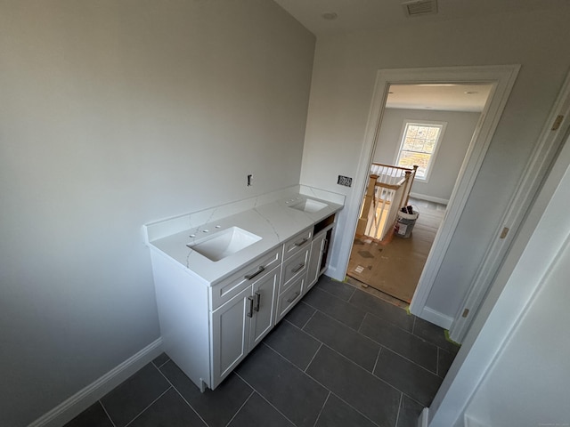 interior space featuring dark tile patterned flooring, a sink, and baseboards