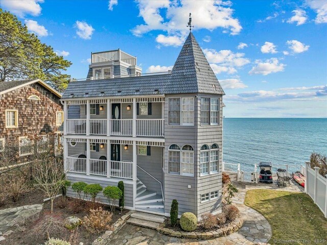 back of property featuring a balcony, a water view, and covered porch