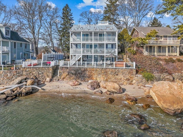 rear view of house with a water view and a balcony