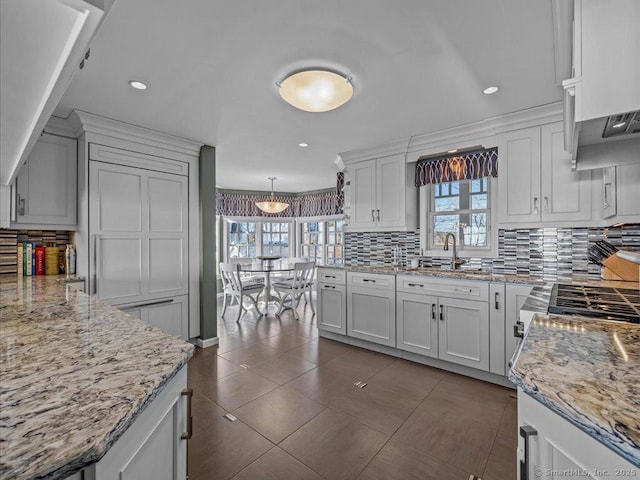 kitchen featuring decorative light fixtures, light stone countertops, decorative backsplash, and white cabinets