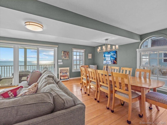 dining space with a water view, a chandelier, and light hardwood / wood-style floors