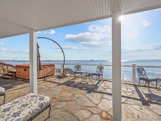 view of patio with a hot tub and a water view