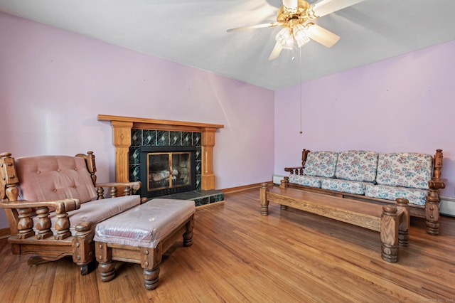 living room featuring light hardwood / wood-style floors, ceiling fan, and a fireplace