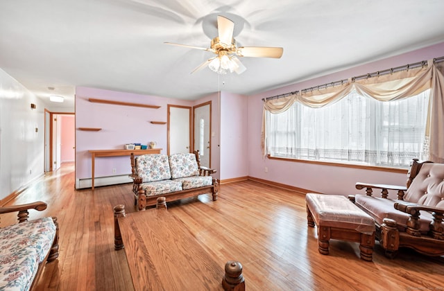 sitting room with a baseboard radiator, light wood-type flooring, and ceiling fan