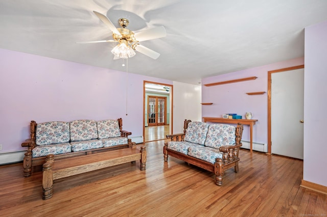 living room with ceiling fan, light hardwood / wood-style floors, and a baseboard heating unit