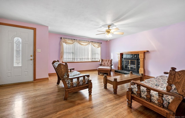 living room with light wood-type flooring, ceiling fan, and a high end fireplace