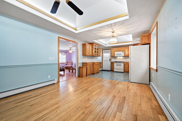 kitchen featuring a baseboard radiator, pendant lighting, a tray ceiling, white appliances, and decorative backsplash