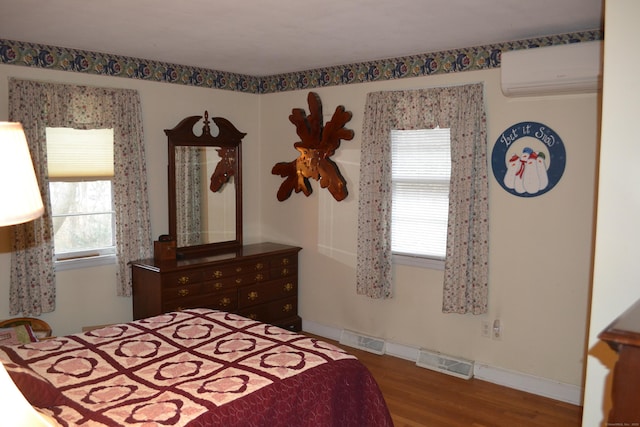 bedroom featuring hardwood / wood-style flooring and a wall mounted AC