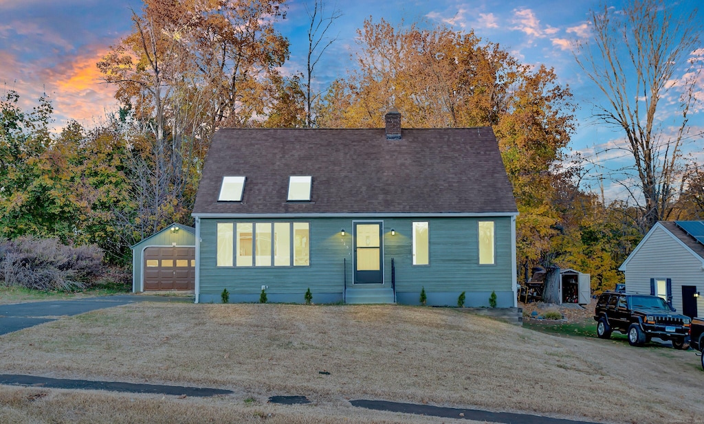 view of front of home with a garage, a yard, and a storage unit