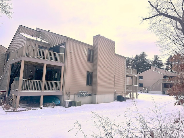 view of snow covered exterior featuring a balcony and central AC