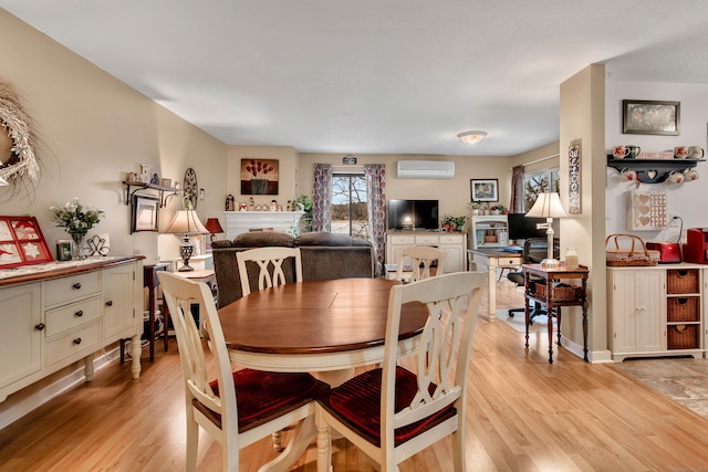 dining room featuring light wood-type flooring and an AC wall unit