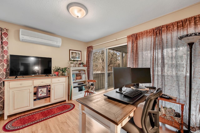 home office with a wall mounted AC, a textured ceiling, and light hardwood / wood-style floors