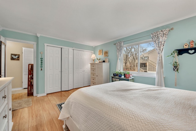 bedroom featuring multiple closets, crown molding, and light hardwood / wood-style floors