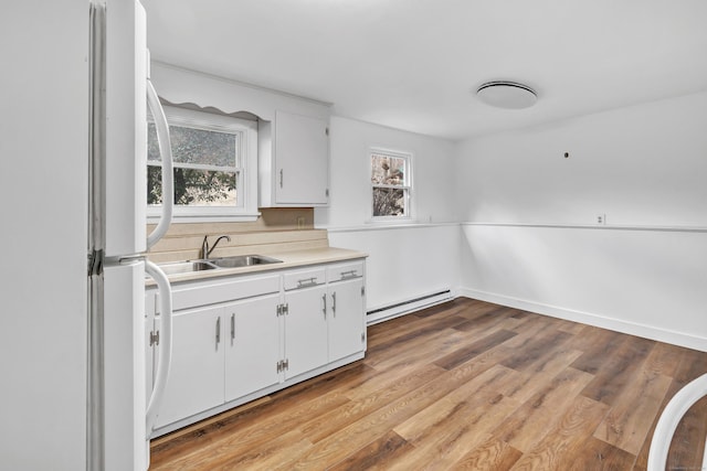 kitchen with white cabinets, a baseboard heating unit, a wealth of natural light, and white refrigerator