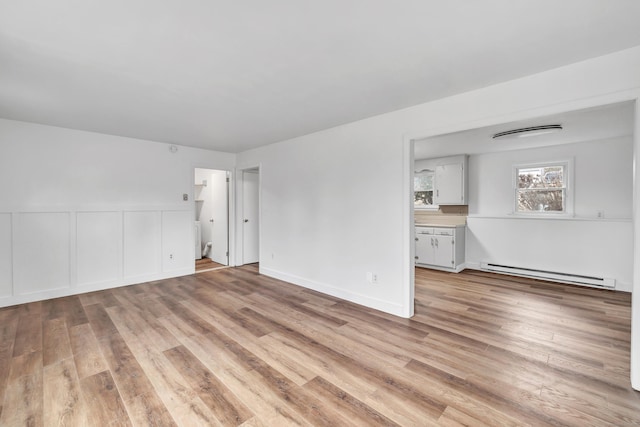 unfurnished room with a baseboard heating unit and light wood-type flooring