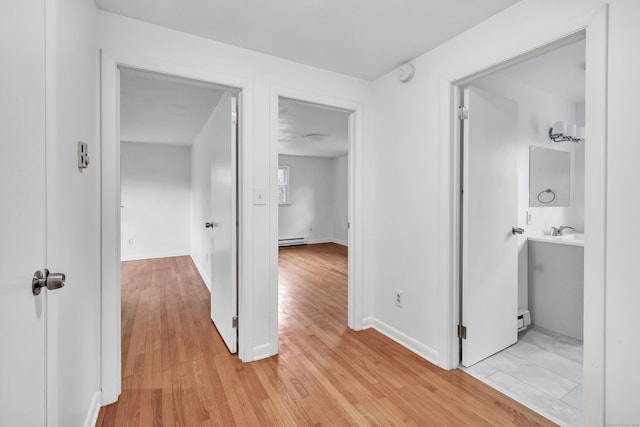 hallway with light wood-type flooring and baseboard heating