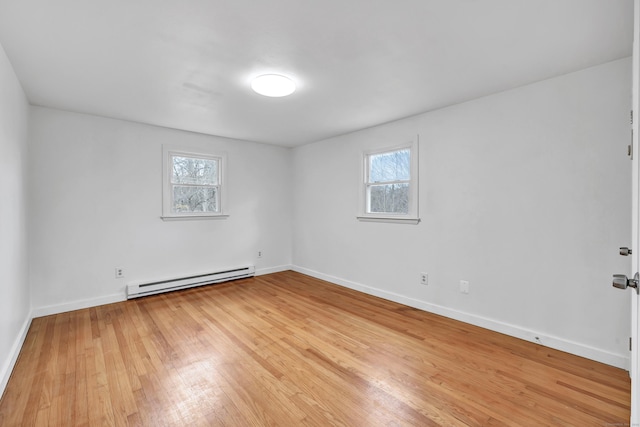 empty room with a baseboard radiator, hardwood / wood-style floors, and a wealth of natural light