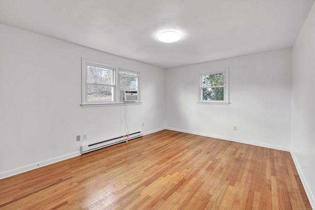 spare room featuring a baseboard heating unit, cooling unit, and light hardwood / wood-style flooring