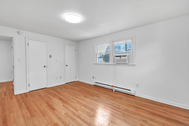 unfurnished bedroom with light wood-type flooring, cooling unit, and a baseboard radiator