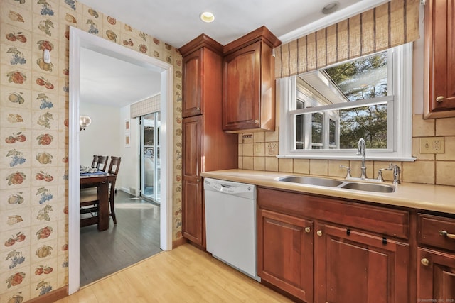 kitchen featuring sink, dishwasher, light hardwood / wood-style flooring, and backsplash