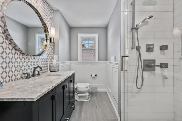 bathroom featuring tiled shower, toilet, and vanity