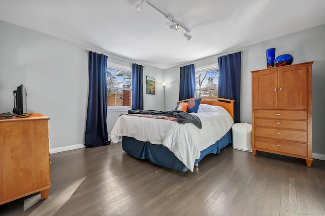 bedroom with rail lighting and dark wood-type flooring