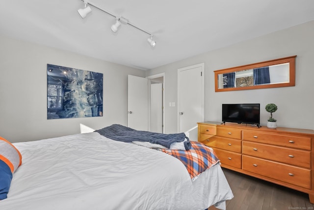 bedroom with rail lighting and dark wood-type flooring