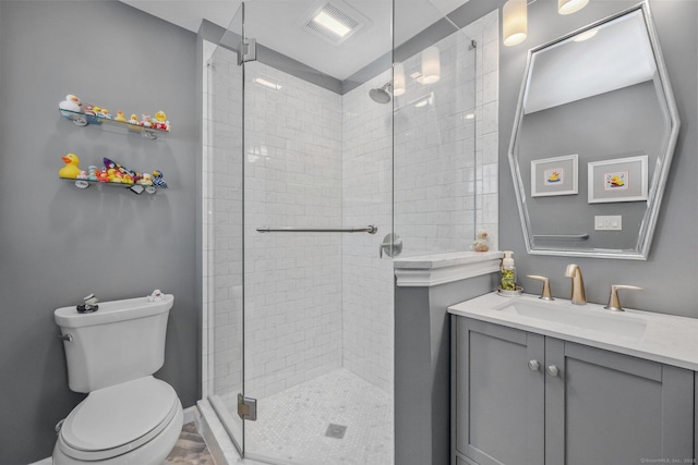 bathroom featuring vanity, toilet, and a shower with shower door