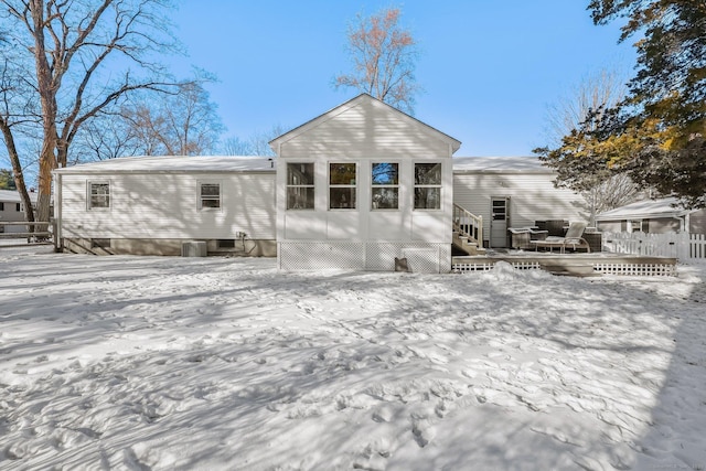 snow covered back of property featuring a deck