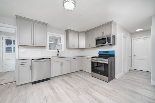 kitchen with appliances with stainless steel finishes, gray cabinetry, and sink