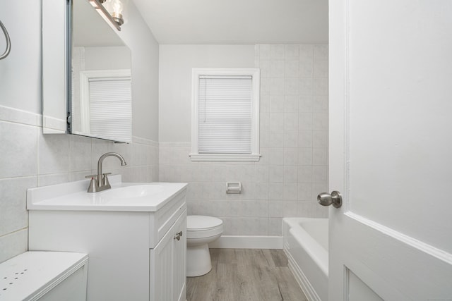 bathroom featuring hardwood / wood-style floors, toilet, vanity, and tile walls