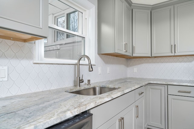 kitchen with dishwasher, sink, light stone counters, and gray cabinets