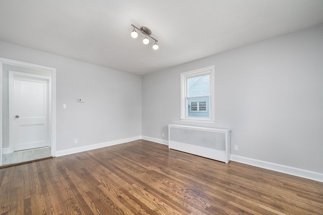 empty room featuring radiator and dark hardwood / wood-style floors