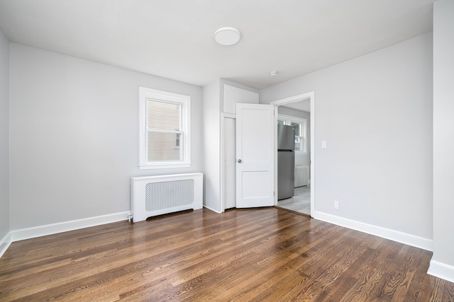 unfurnished room featuring radiator and dark hardwood / wood-style floors