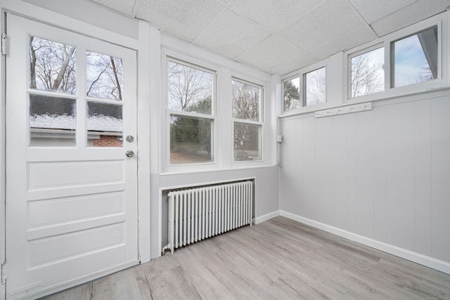 unfurnished sunroom with radiator and a drop ceiling