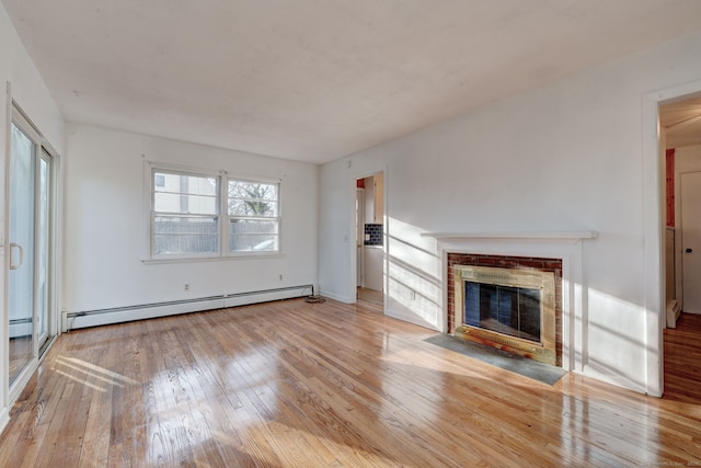 unfurnished living room featuring a brick fireplace, baseboard heating, and light hardwood / wood-style flooring