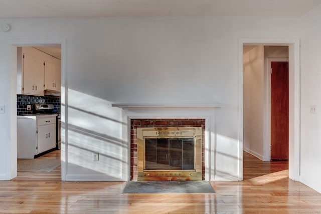 unfurnished living room with a brick fireplace and light wood-type flooring