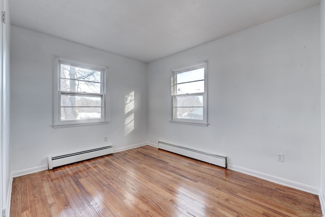 unfurnished room with a baseboard radiator, plenty of natural light, and light wood-type flooring