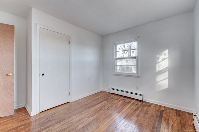 empty room with light hardwood / wood-style flooring and a baseboard radiator