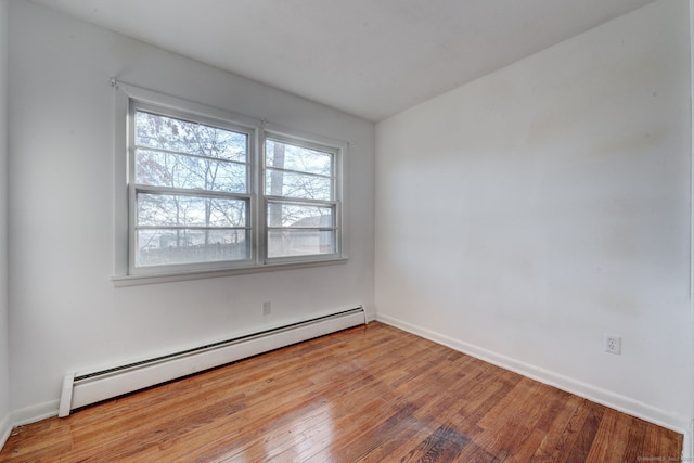 empty room with baseboard heating and light hardwood / wood-style flooring