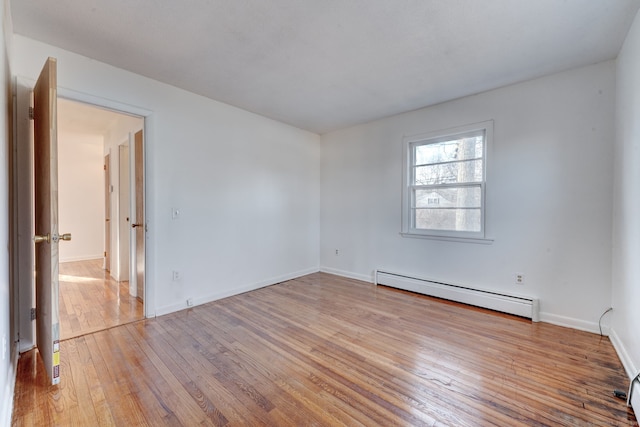 unfurnished room featuring a baseboard heating unit and light hardwood / wood-style flooring