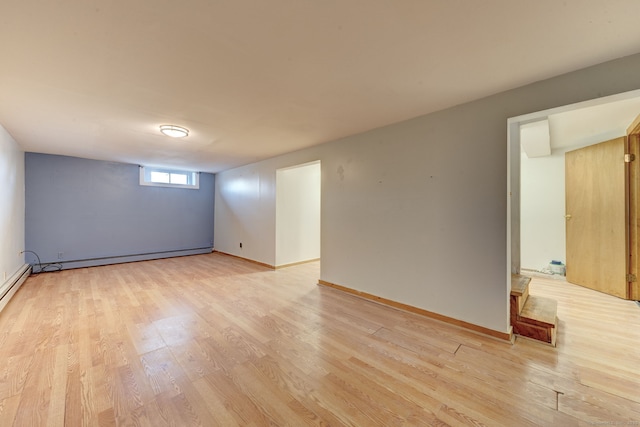 unfurnished room featuring baseboard heating and light wood-type flooring