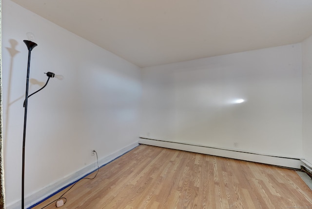 empty room featuring light wood-type flooring and a baseboard radiator