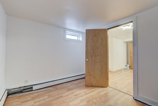 empty room with a baseboard radiator and hardwood / wood-style floors