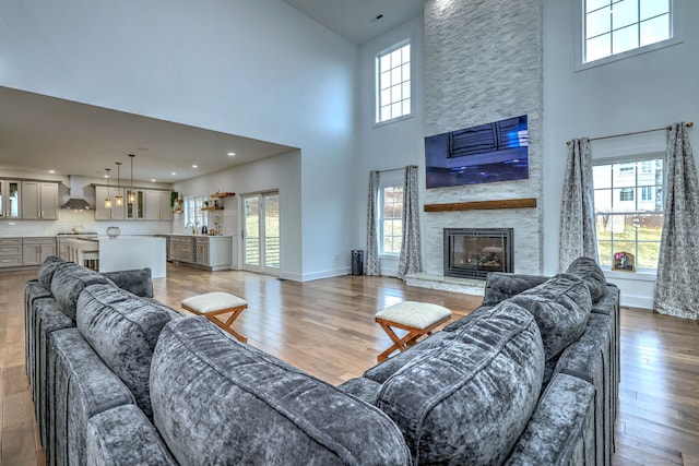 living room featuring light wood-type flooring, sink, a fireplace, and a high ceiling